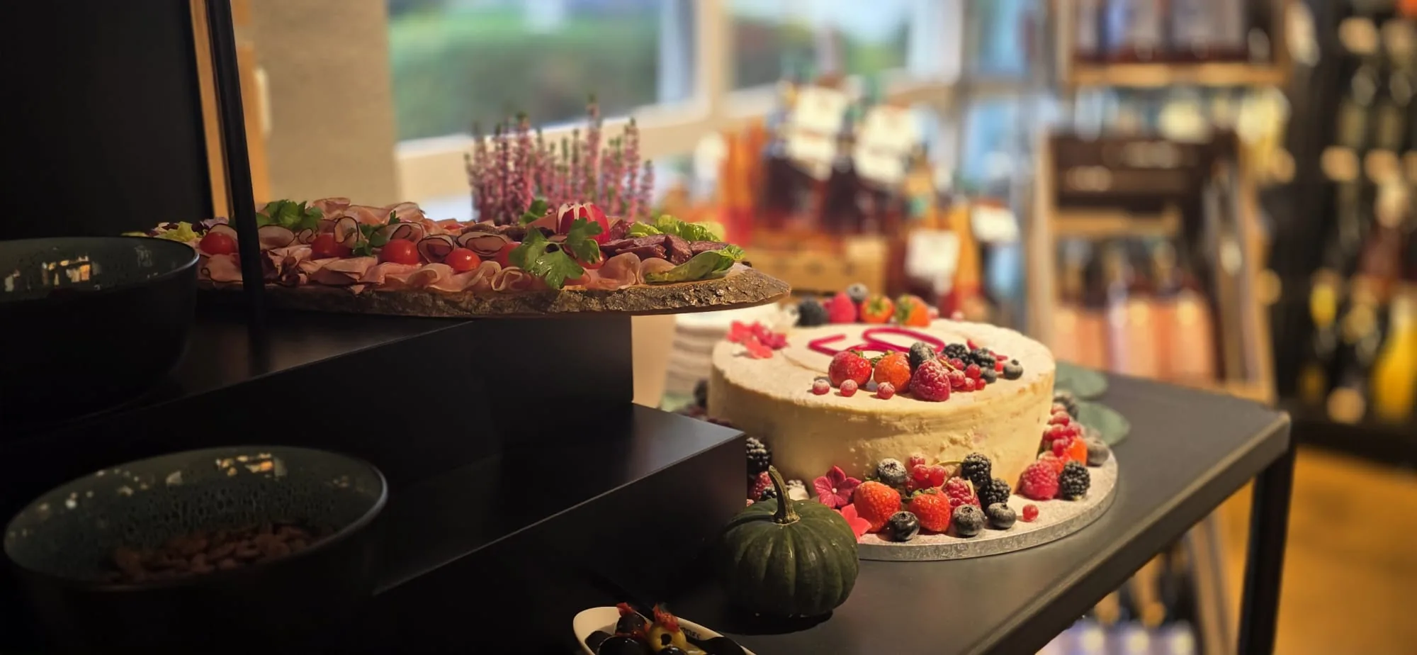 Festlich angerichtetes Buffet mit Wurstplatte und herbstlicher Beeren-Torte bei einer Feier im Laden
