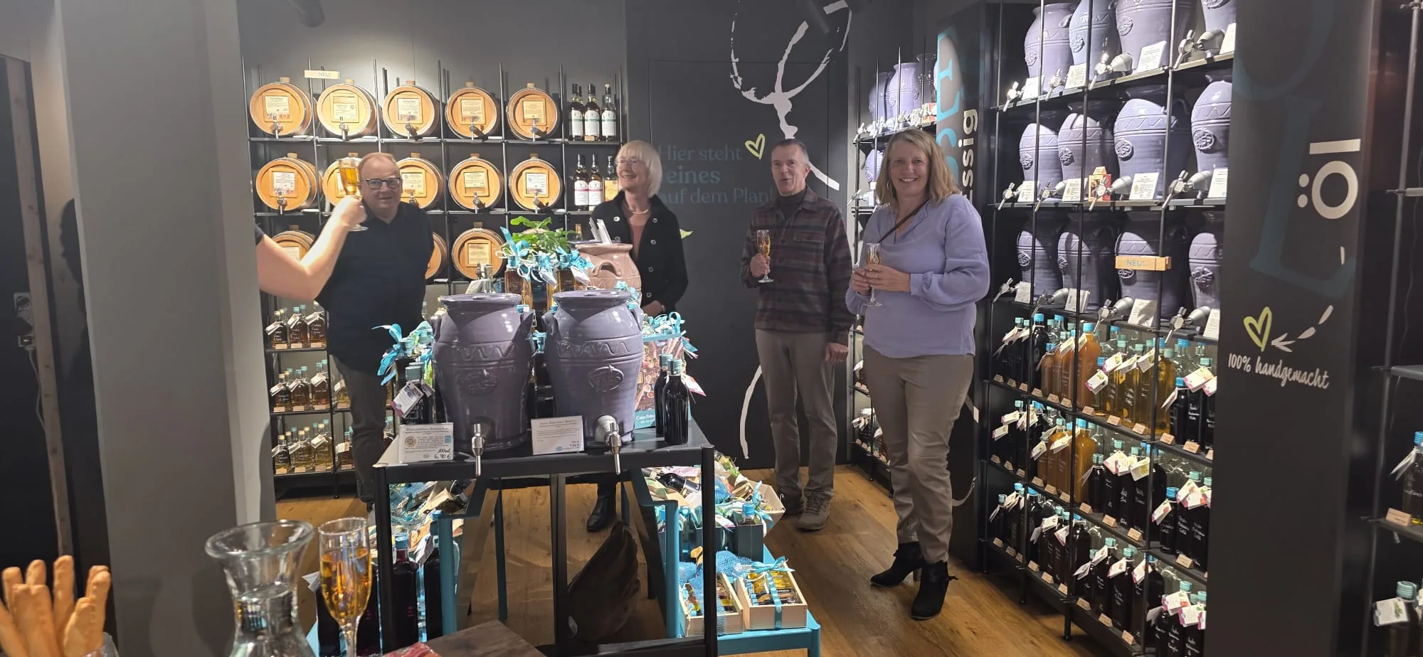 Gruppe stößt bei einem Tasting mit Sekt zwischen den Essig- und Öl-Amphoren an