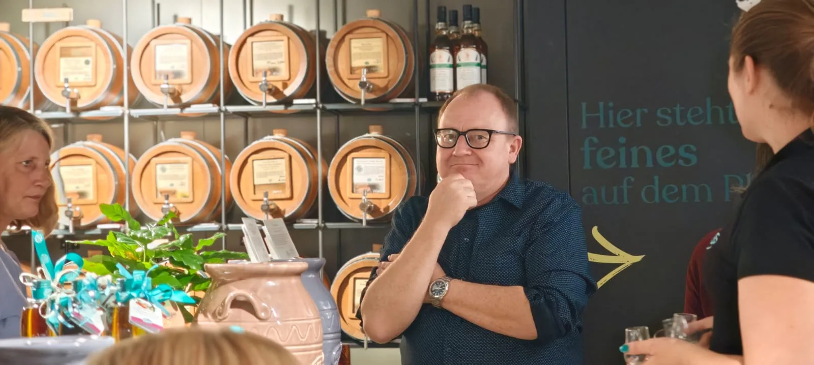 Gast lauscht den Erläuterungen vor der Whiskyfass-Wand bei einem Tasting in Olching